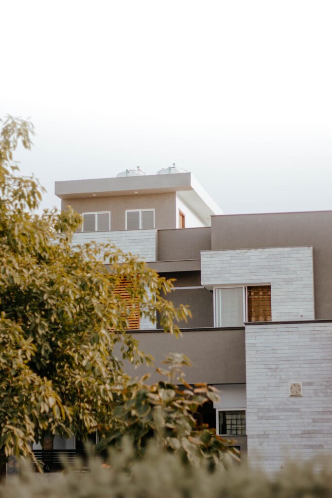 A modern residential building surrounded by greenery under a clear blue sky.